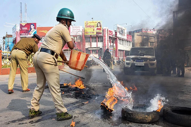 A police personnel extinguishes a burning tyre left by a protestor in Agartala on Thursday.