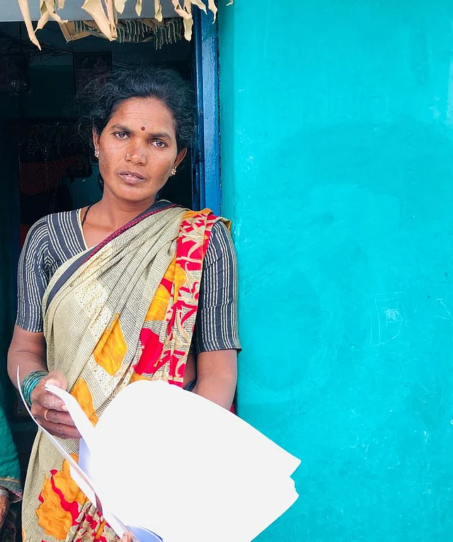 Jayamma stands here with reports of her son’s kidney problems, stating that he would not work much cause of his health issues.