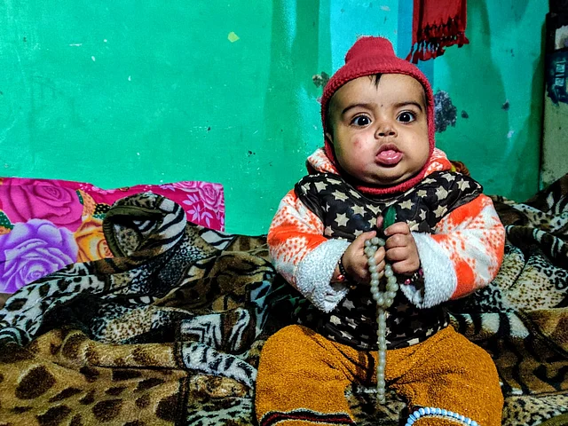 Anas’ infant son sits next to his mother, Bushra Anas, who is observing the period of mourning called <i>Iddat</i>. 