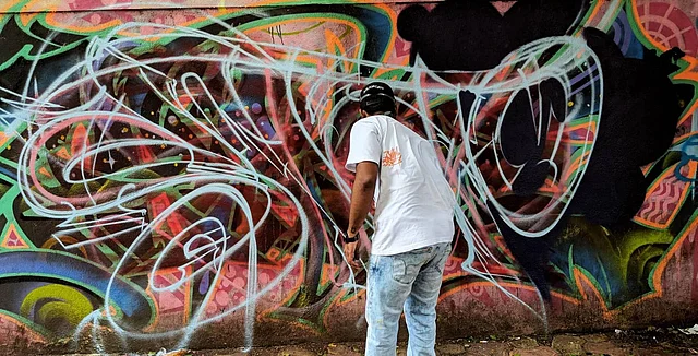 Zake, a graffiti artist, painting one of the walls near Mumbai’s bird song cafe. 