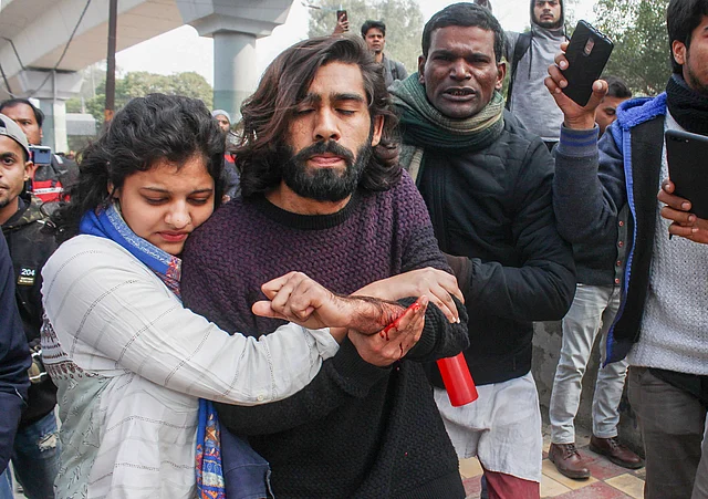 A student of the Jamia Millia Islamia university, injured after a teenager opened fire during an anti-CAA protest, is assisted towards a hospital in New Delhi on Thursday, 30 January.
