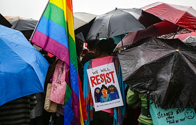 A member of LGBTQ community carries a placard while standing with others holding umbrellas as it rains during a rally to protest against a new citizenship law that opponents say threatens India’s secular identity, in Kolkata, India, Friday, 3 Jan.