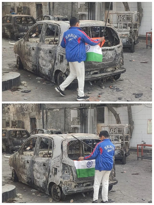 A boy places the national flag on the charred remains of a vehicle in Bhajanpura