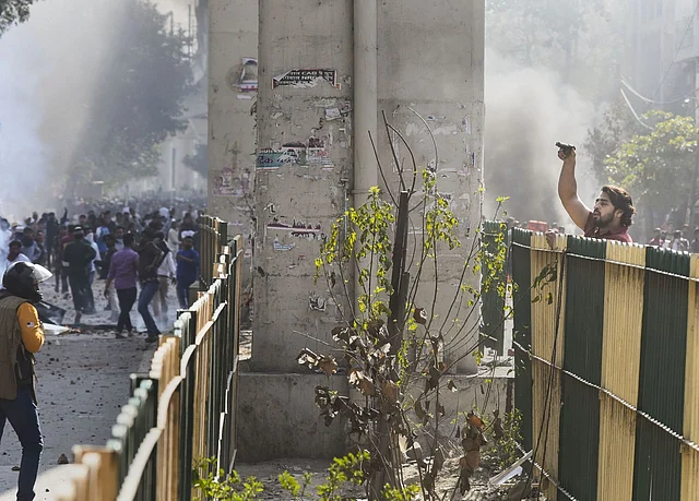 A protestor brandishes a pistol during clashes between a group of anti-CAA protestors and supporters of the new citizenship act, at Jafrabad in north-east Delhi