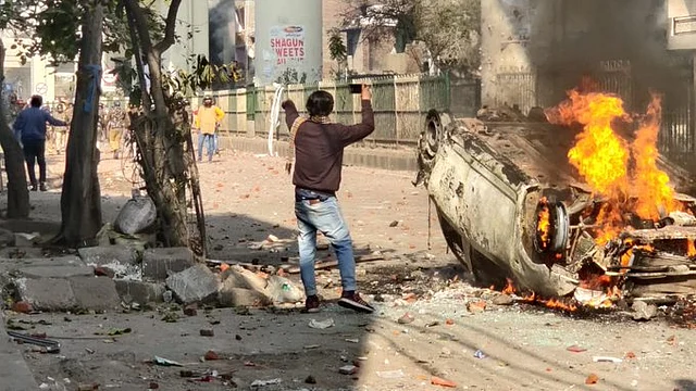 A burning vehicle marks the threshold between Anti & pro-CAA protestors on 23 February