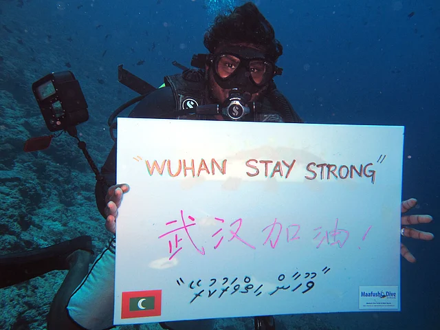 A local diver cheers for China’s Wuhan atMaafushi’s Cocoa Reef, Maldives.