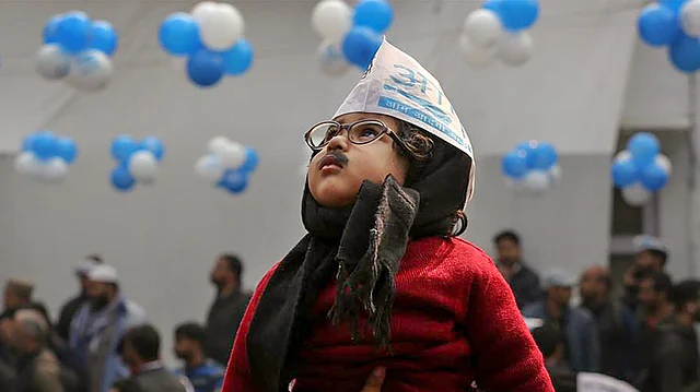 Aam Aadmi Party workers hold a child dressed as AAP convener Arvind Kejriwal as they celebrate the party’s victory in the Delhi Assembly polls, at party headquarters in New Delhi, on Tuesday, 11 February. 