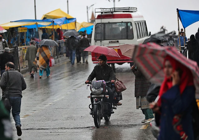 Kashmiri commuters use umbrellas as it rains in Srinagar, Kashmir, Thursday, 12 March 2020.