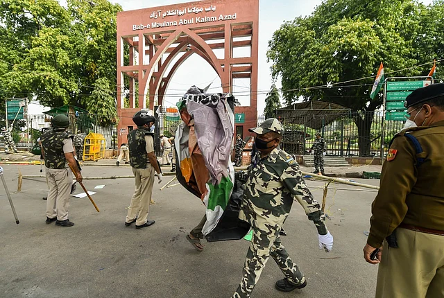 Police and paramilitary personnel clear the site of protest at Jamia College.