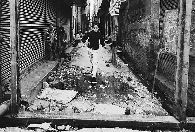 A kid playing near the entrance of his lane where a new gate is being built for safety in Mustafabad.