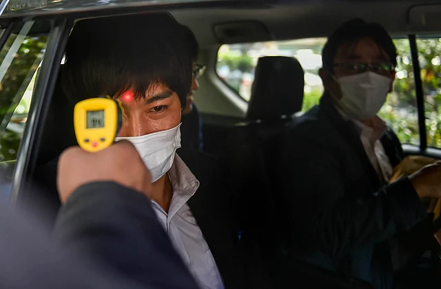 An official uses a thermal screening device on an employee in the wake of deadly coronavirus, at an office in New Delhi, Thursday, 12 March 2020.