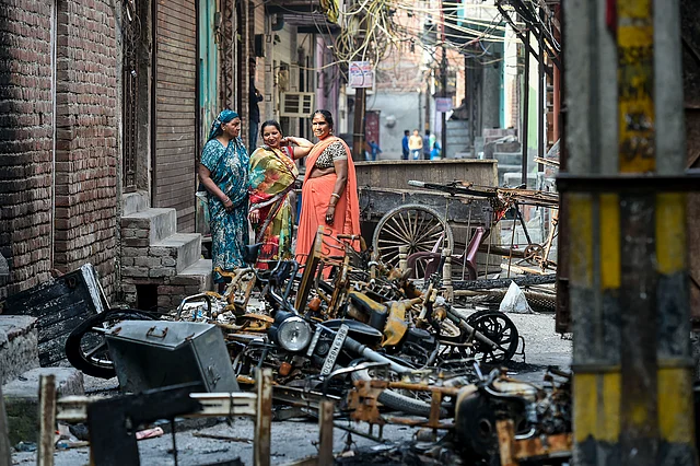 Women stand beside charred remains of vehicles and vandalised properties at Shiv Vihar in Northeast Delhi, Monday, 2 March 2020. The riots in areas like Jaffrabad, Maujpur, Gokalpuri, Khajuri Khas, Bhajanpur and few others.