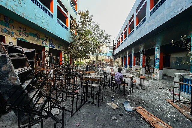 A man sits on bench at a school, damaged during the recent communal violence, at Shiv Vihar in Northeast Delhi, Monday, 2 March, 2020. 