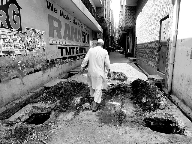 A Muslim man crosses by the pits dug to erect pillars for iron gates in Gali No 20 in Mustafabad.