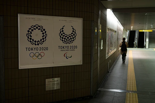 A commuter leaves a train station adorned with posters promoting the Tokyo 2020 Olympics in Tokyo, Monday, March 23, 2020.