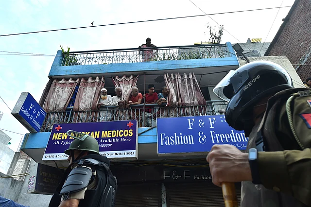 Locals look on as a heavy deployment of police force is put in place in Shaheen Bagh.