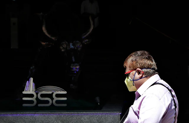 An Indian man wearing a mask walks past the Bombay Stock Exchange (BSE) building in Mumbai, India, Friday, 13 March 2020.