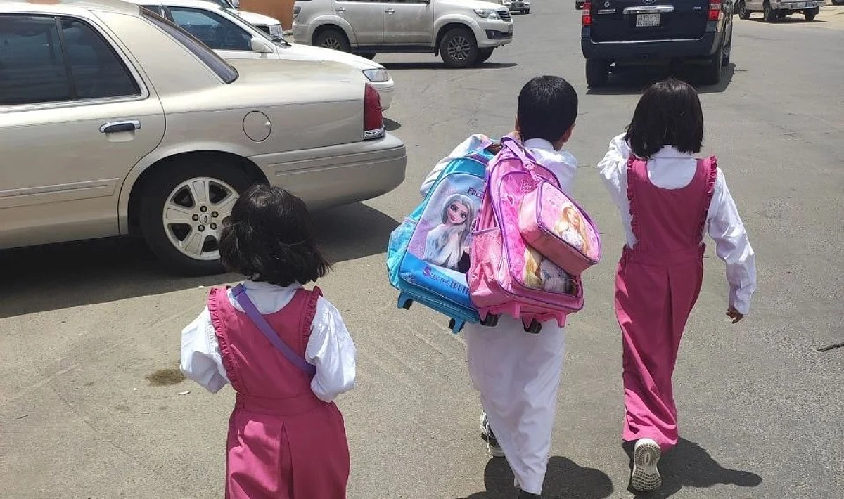 الطفل مشعل الشهراني يحمل حقائب أختيه