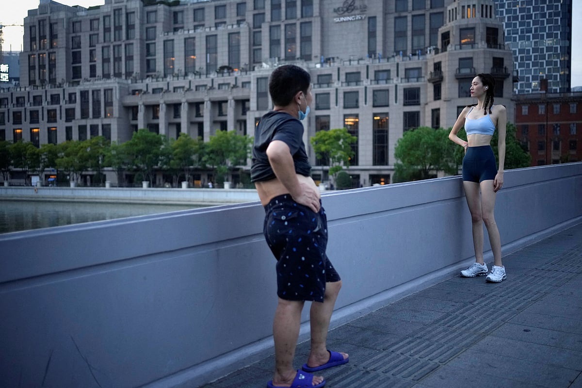 A woman poses for a photo on a bridge near the Bund amid a heatwave warning, as Shanghai switches off lights along a popular waterfront to conserve energy in Shanghai, China, August 22, 2022. 