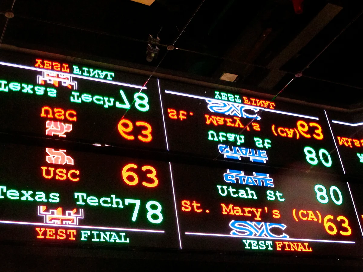 FILE This Nov. 20, 2018 file photo shows a scrolling video board with basketball scores reflected in the ceiling of the new sports book at Resorts Casino in Atlantic City, N.J. The race to legalize sports betting is on now that the U.S. Supreme Court has allowed it in all 50 states, but will it provide enough extra tax revenue to make much of a difference for schools, roads or pension debt? (AP Photo/Wayne Parry)