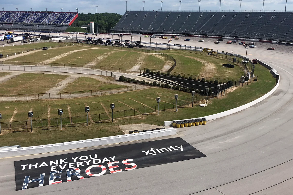 Cars go through a turn past a sign thanking people working during the coronavirus pandemic at Darlington Raceway Sunday, May 17, 2020, in Darlington, S.C. NASCAR, which has been idle for 10 weeks because of the pandemic, made its return with the Real Heroes 400 Nascar Cup Series auto race.
