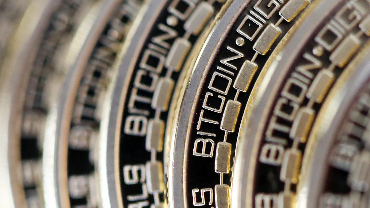 The embossed word Bitcoin sits on the edge of Bitcoins stacked (Photographer: Chris Ratcliffe/Bloomberg)