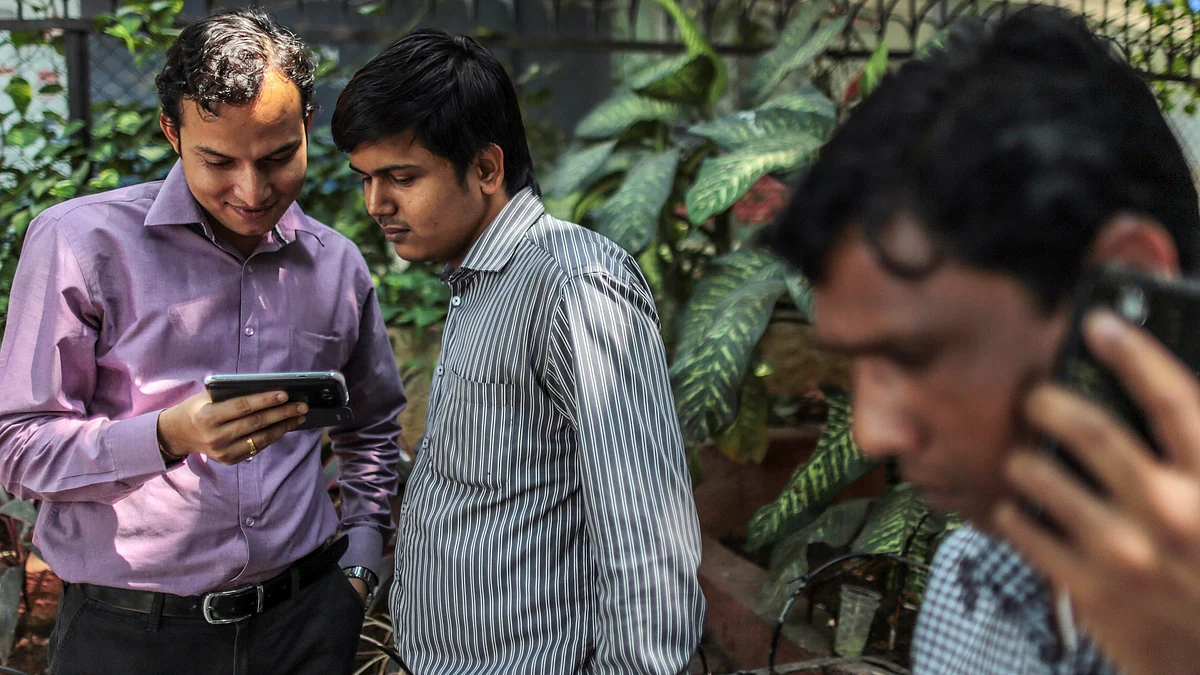 Office workers look at mobile phone during their lunch break in the Nariman Point area of Mumbai (Photographer: Dhiraj Singh/Bloomberg)