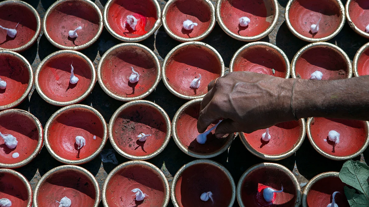 A worker places cotton wicks in Diwali diyas, earthenware lamps, on a street near Sarojini Market in New Delhi (Photographer: Prashanth Vishwanathan/Bloomberg)
