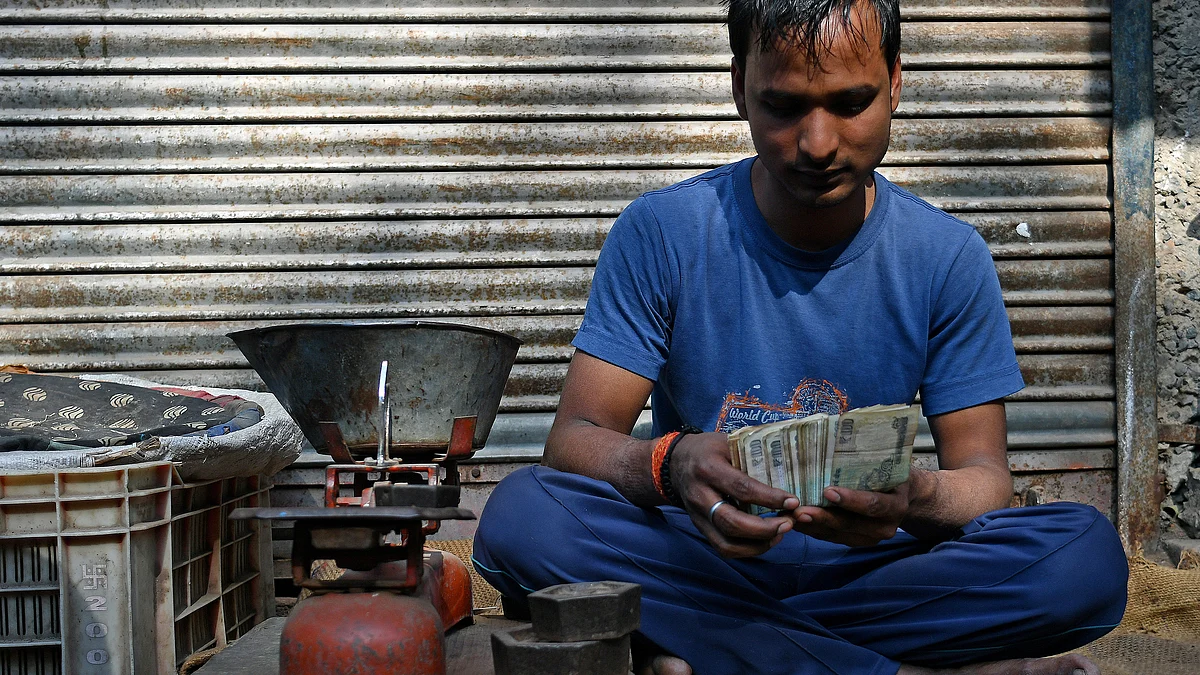 A vendor counts one hundred rupee banknotes at a wholesale market in Delhi (Photographer: Anindito Mukherjee/Bloomberg)