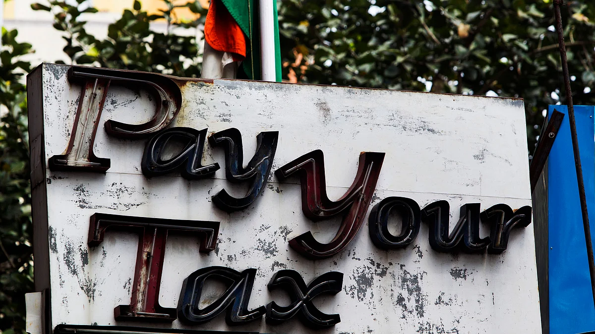A sign reading “Pay Your Tax” sits outside the income tax office in Kolkata, India (Photographer: Brent Lewin/Bloomberg)
