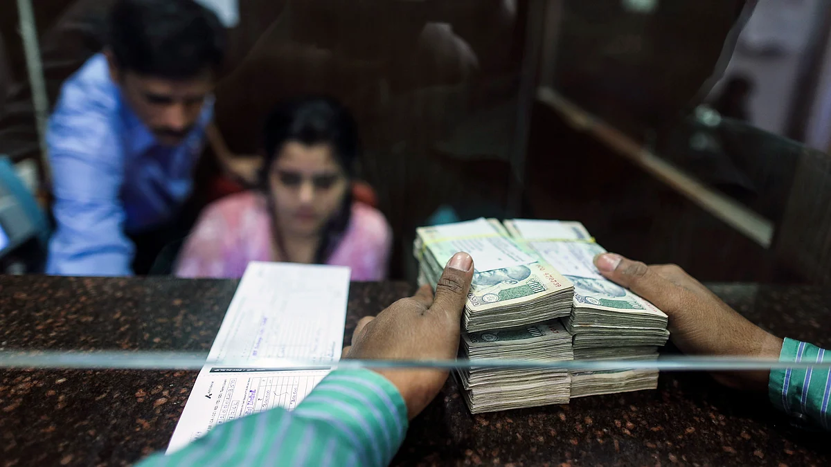 A customer waits to deposit Indian 100 rupee banknotes at a counter (Photographer: Dhiraj Singh/Bloomberg)