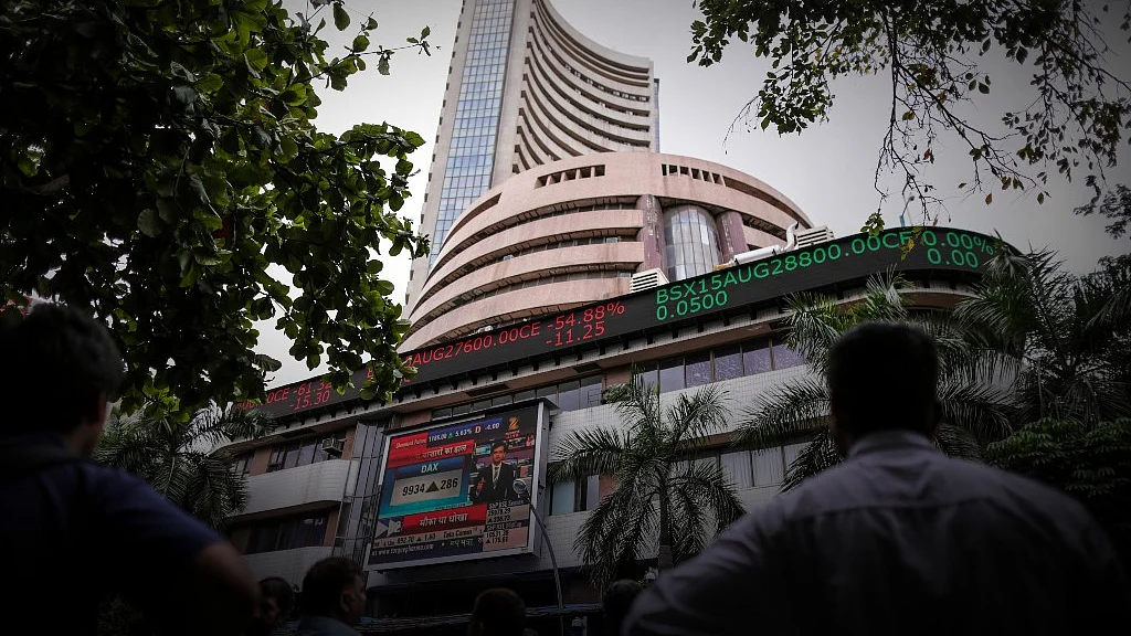 Men look up at an electronic ticker board that indicates stock figures at the Bombay Stock Exchange (BSE) in Mumbai. Photographer: Dhiraj Singh/Bloomberg.