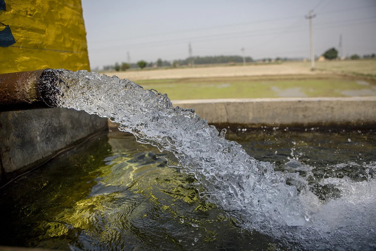 Water flows from a pipe into a concrete basin near a rice field in Karnal, Haryana, India, on May 19, 2016. (Photographer: Prashanth Vishwanathan/Bloomberg)