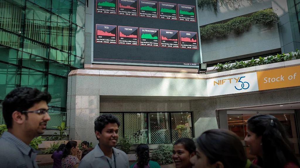 Employees stand at in front of an electronic board that indicates the latest stock figures at the the National Stock Exchange in India. (Photographer: Dhiraj Singh/Bloomberg)