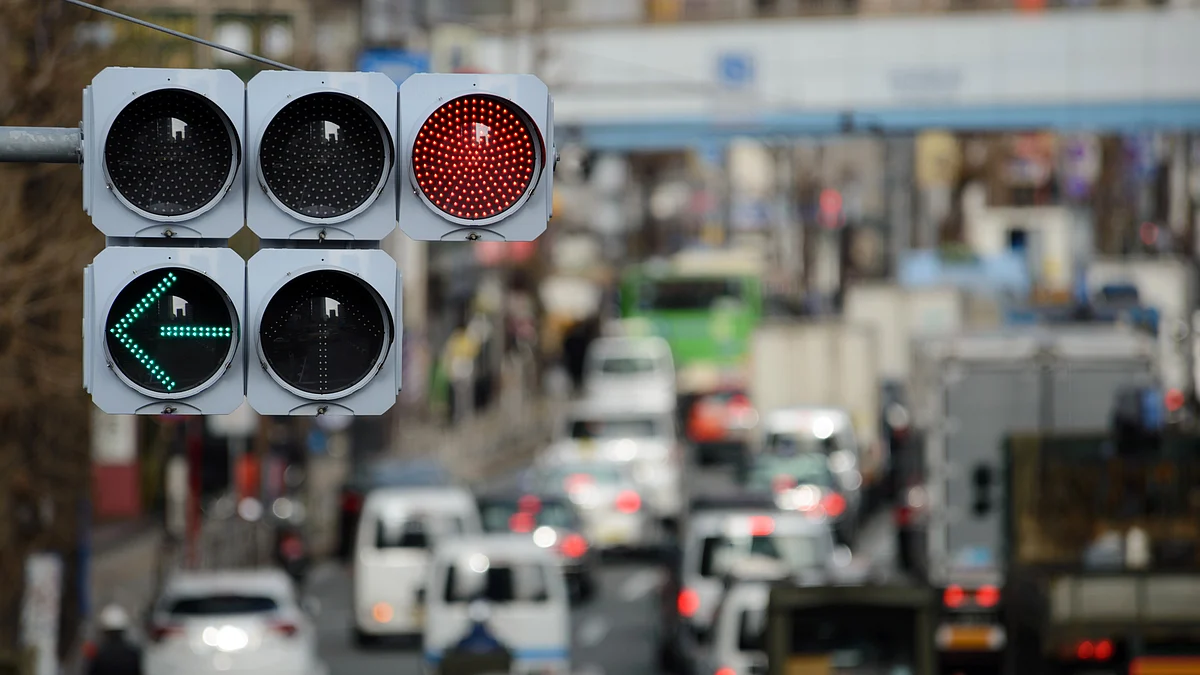 A red light and green arrow are displayed on a light-emitting diode (LED) traffic signal above vehicles moving along a road (Photographer: Akio Kon/Bloomberg)