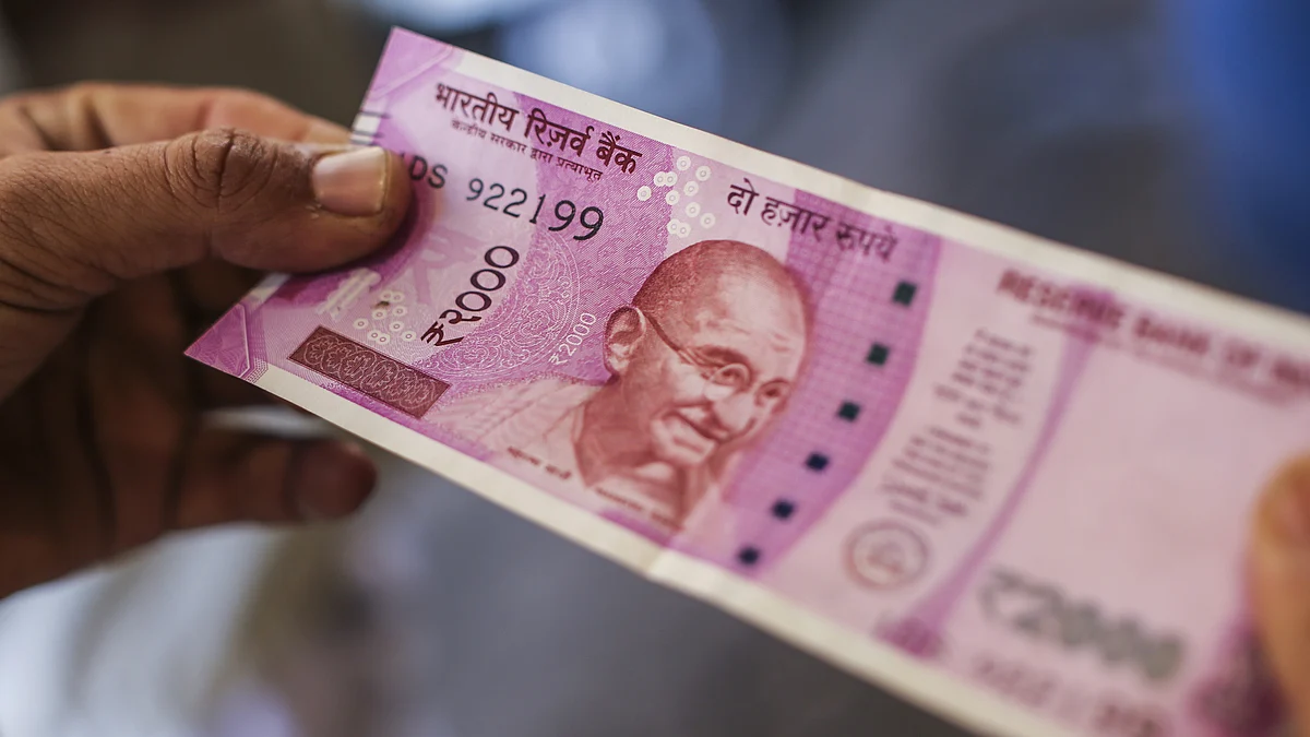 A man holds a two thousand Indian rupee banknote (Photographer: Dhiraj Singh/Bloomberg)