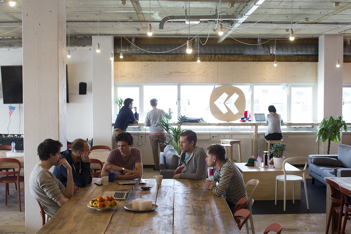 Employees sit around a table in a workspace (Photographer: Jasper Juinen/Bloomberg)