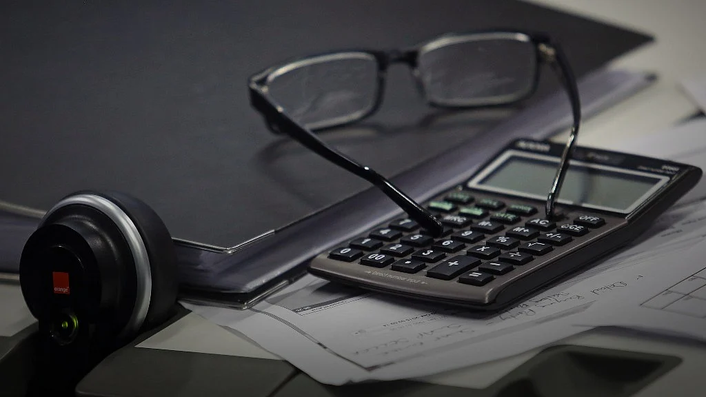 A fixed line telephone and a calculator sit next to a pair of spectacles. (Photographer Chris Ratcliffe/Bloomberg)