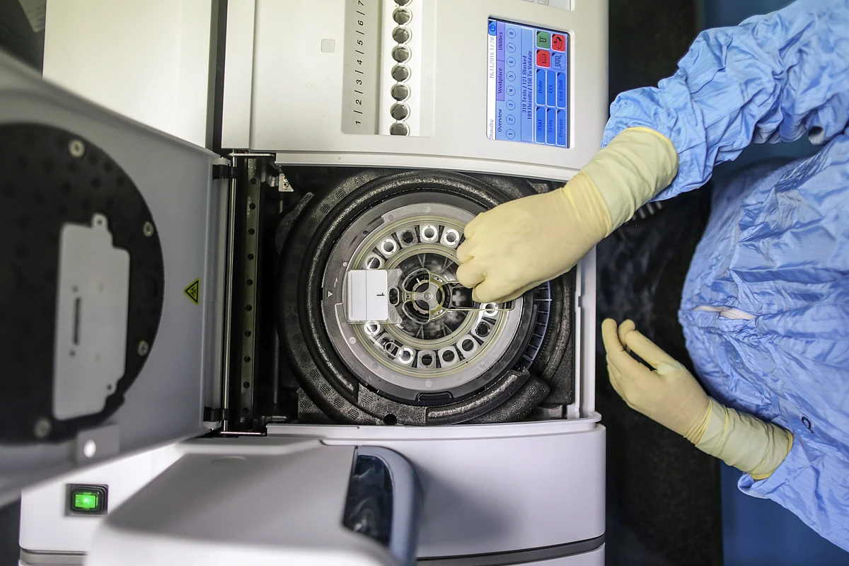 An employee in protective clothing uses a centrifuge in a research and development center. (Photographer: Dhiraj Singh/Bloomberg)