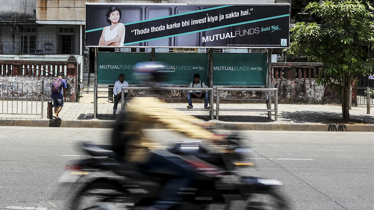 A motorcyclist passes passengers sitting next to an advertisement for the Mutual Funds Sahi Hai campaign (Photographer: Dhiraj Singh/Bloomberg)