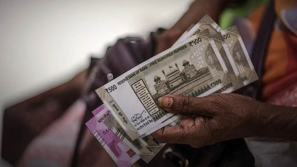 A customer holds Indian rupee banknotes (Photographer: Dhiraj Singh/Bloomberg)