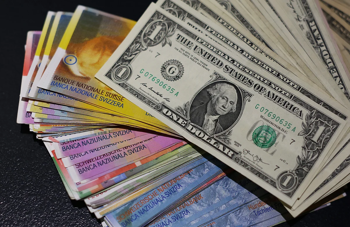 Multiple denomination U.S. dollar bills sit on top of Swiss franc bank notes (Photographer: Chris Ratcliffe/Bloomberg)