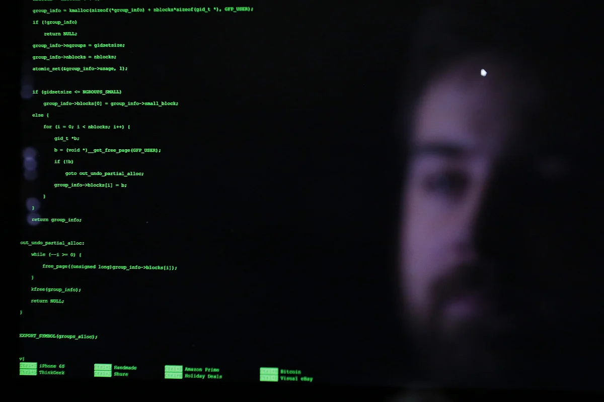 The face of an attendee is reflected in a laptop computer screen alongside code as he participates in the TechCrunch Disrupt London 2015 Hackathon in London, U.K. (Photographer: Luke MacGregor/Bloomberg) 