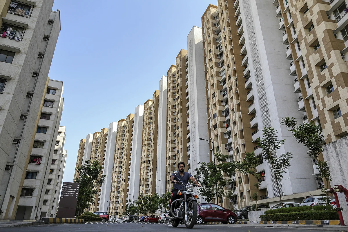 A motorcyclist ride past residential apartment buildings on the outskirts of Mumbai, India. (Photographer: Dhiraj Singh/Bloomberg)