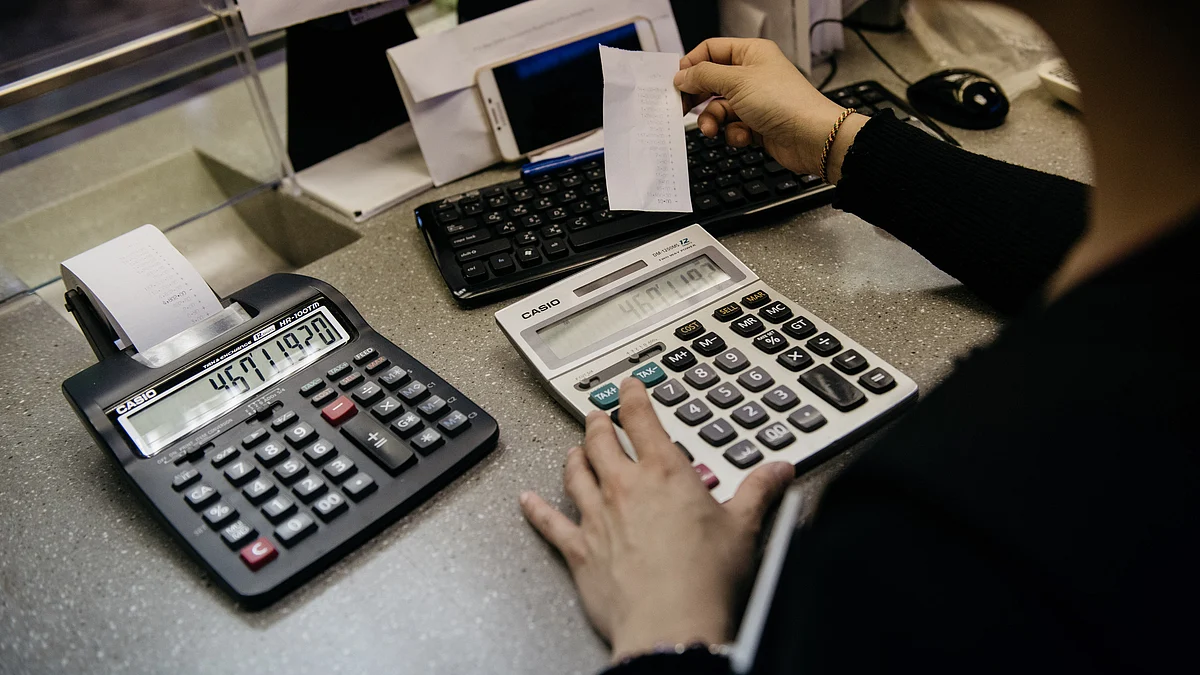 An employee uses a calculator in a store. (Photographer: Anthony Kwan/Bloomberg)