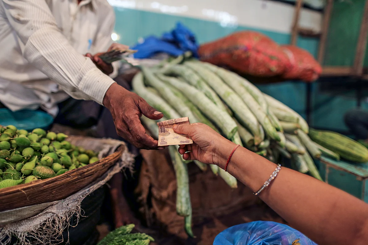 A customer hands over an Indian ten rupee banknote to a vendor at a vegetable market in Mumbai, India. (Photographer: Dhiraj Singh/Bloomberg)