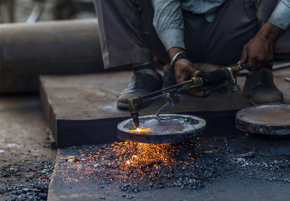 A worker uses a cutting torch in a workshop in a steel and iron market area of New Delhi. (Photographer: Prashanth Vishwanathan/Bloomberg)