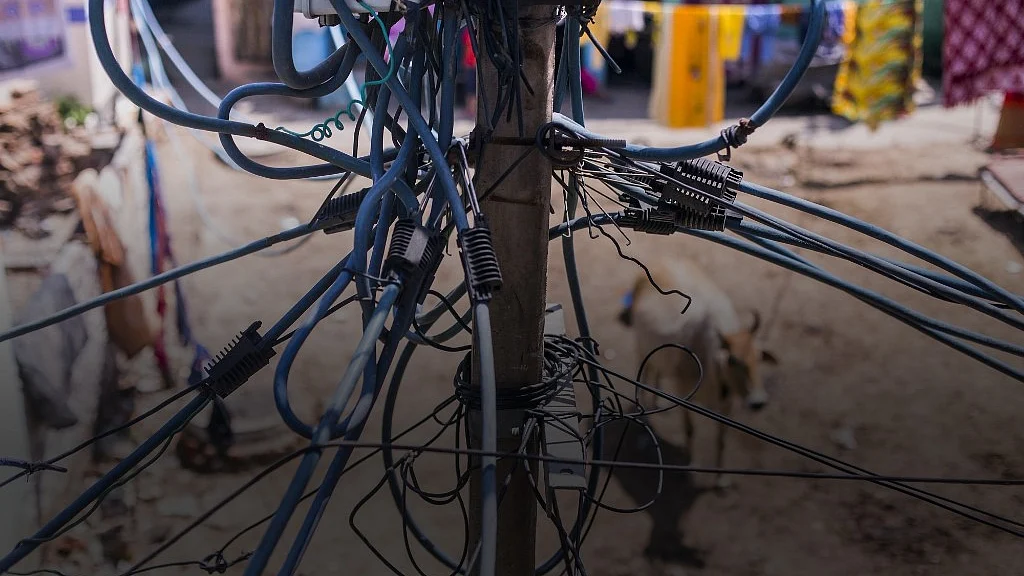 Utility and power cables hang from a pole in the Sanjay Basti slum in New Delhi. (Photographer: Prashanth Vishwanathan/Bloomberg) 