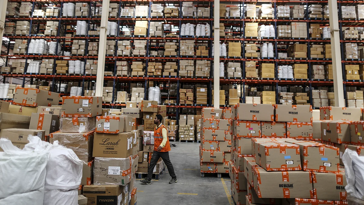 An employee walks past boxes stacked on pallets at a warehouse. (Photographer: Dhiraj Singh/Bloomberg)