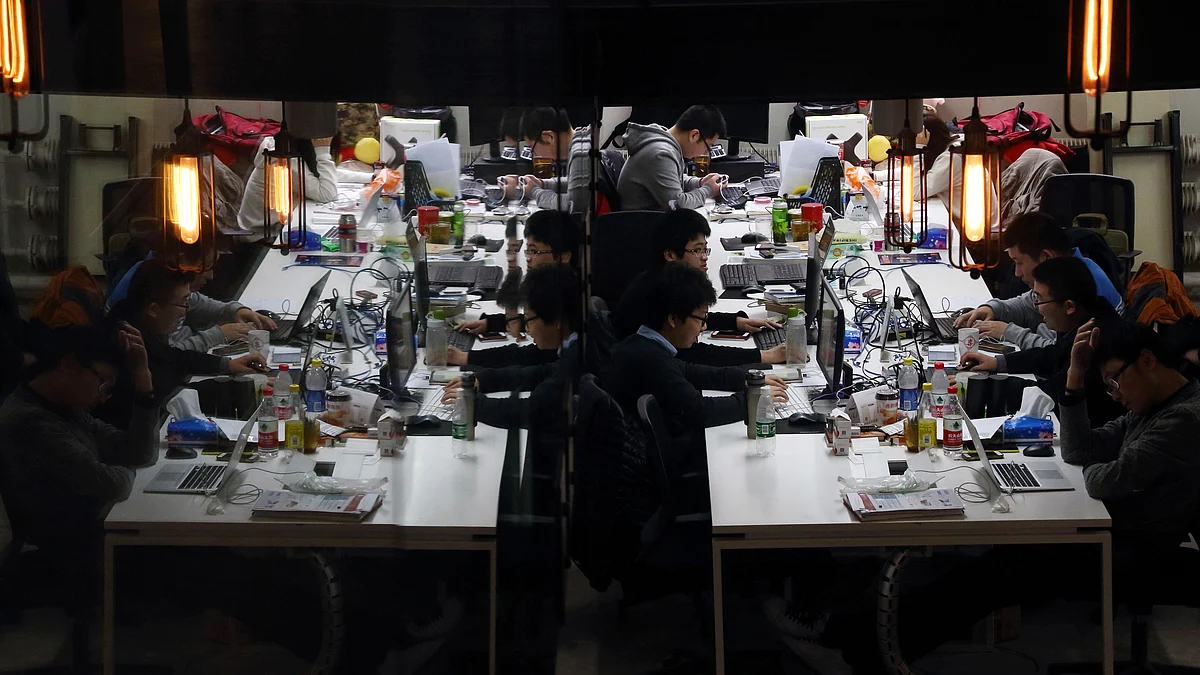 Workers using computers at their desks are reflected in a glass door inside Tech Temple, a co-working space for start-up companies sponsored by Infinity Ventures Partners, in Beijing, China (Photographer: Tomohiro Ohsumi/Bloomberg)